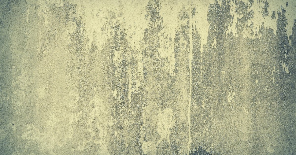 Close-up van een grijsgroene wand met ruwe, decoratieve stucwerkstructuur